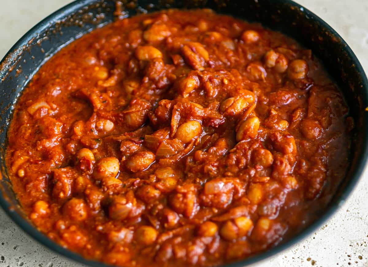 black cooking pot beige ceramic table with spicy Italian 'Nduja beans inside