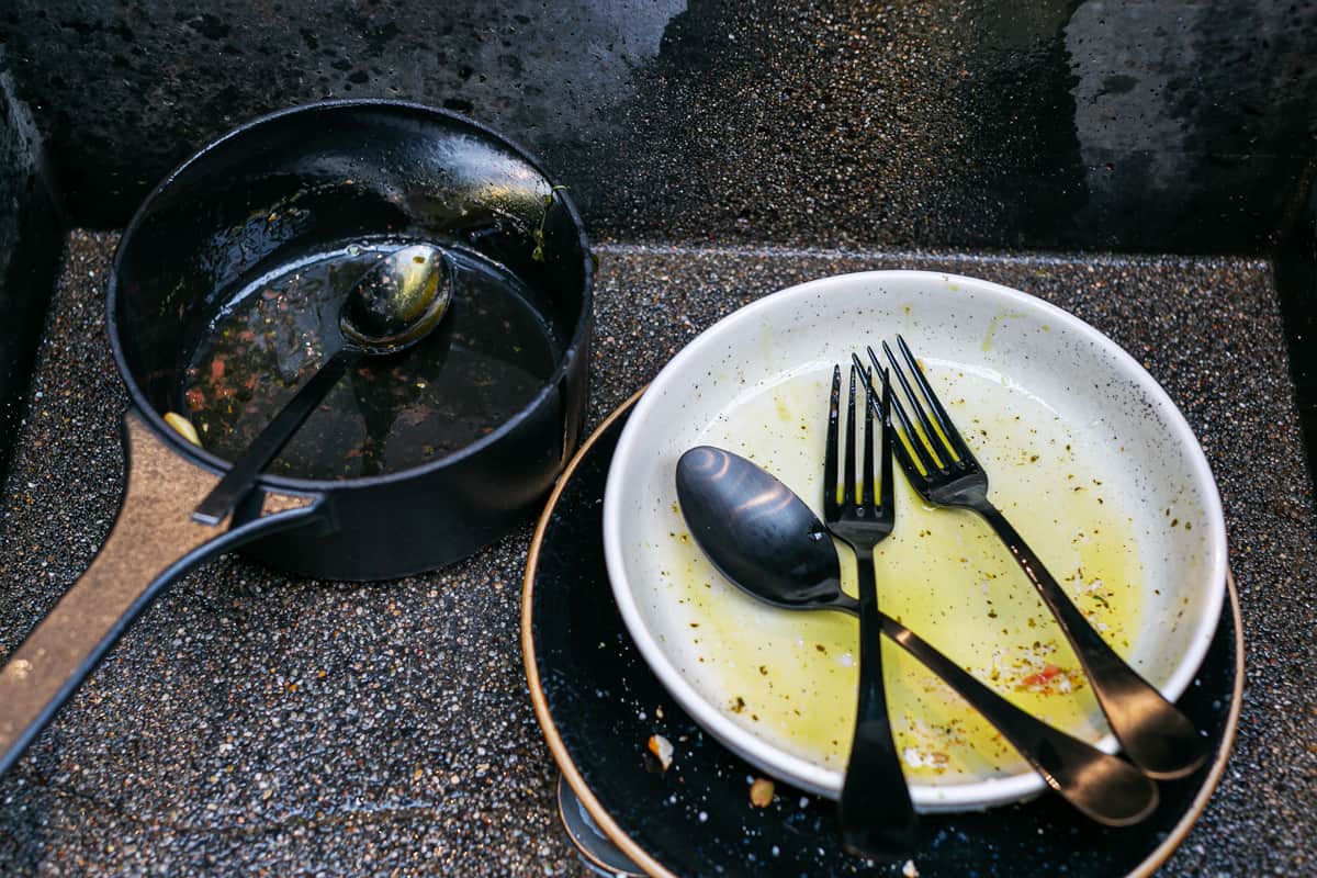 empty pasta bowls and a saucepan from a dinner sitting in the kitchen sink